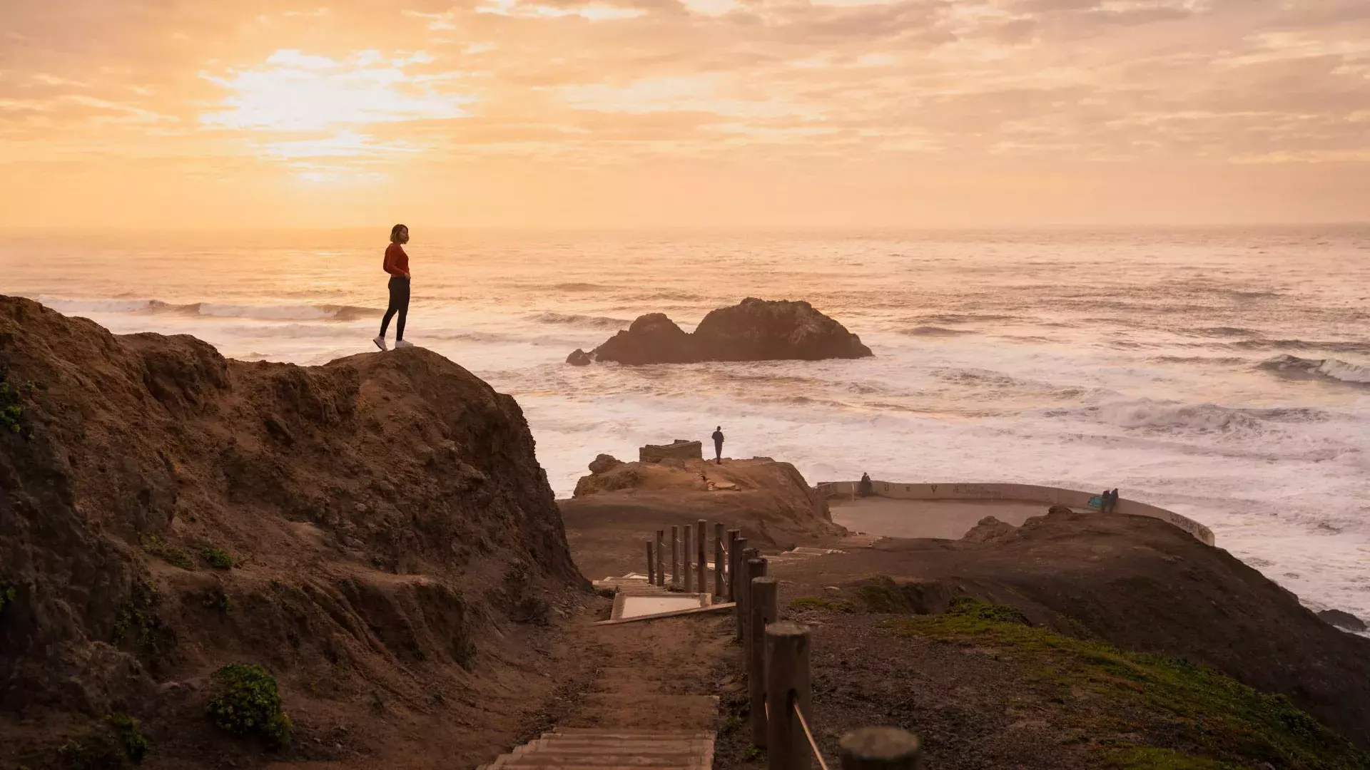 Duas pessoas estão em cima de pedras com vista para o oceano em Sutro Baths, em São Francisco.