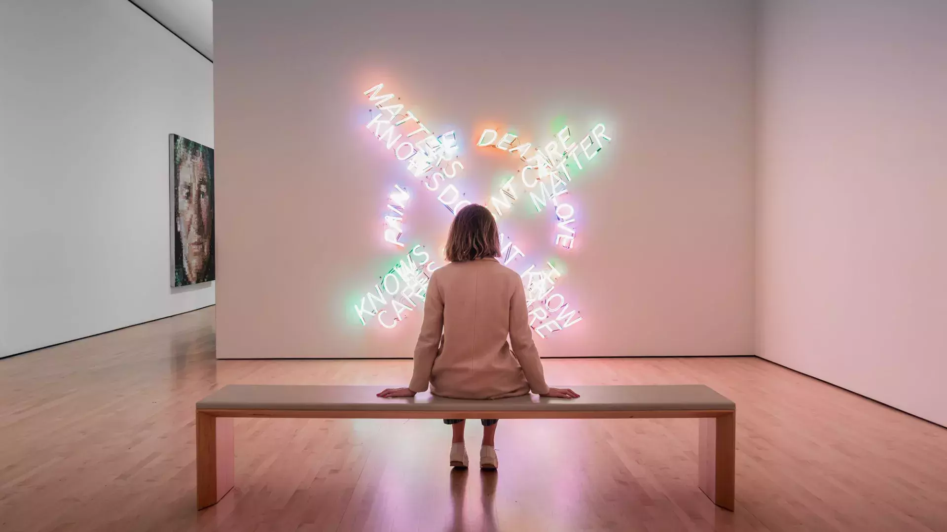 Uma mulher, sentada em um banco, observa uma obra de arte contemporânea de luz no SF MOMA, em São Francisco.