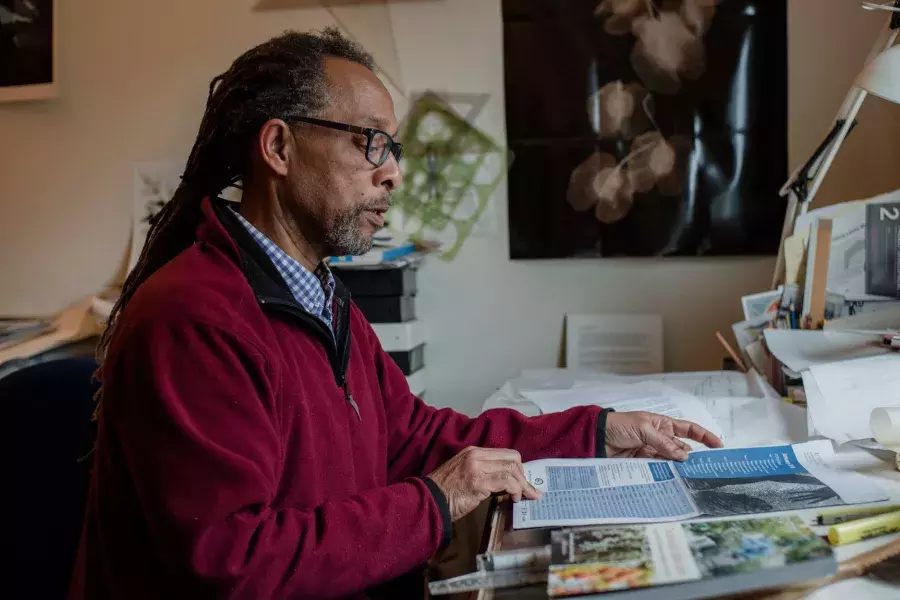 Ron Moultrie Saunders sitting at his desk reading