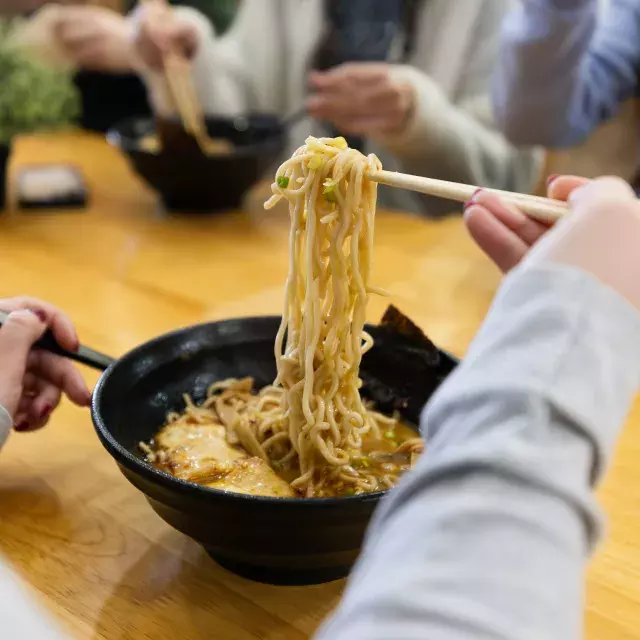 箸で丼からラーメンを持ち上げる人